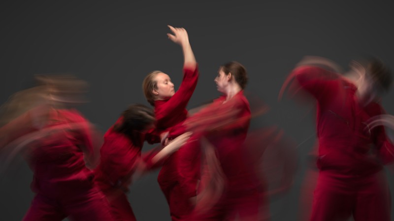 A blurred image of dancers in red jumpsuits
