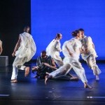Se&aacute;n Curran Company dancers dressed in white perform onstage against a blue background.