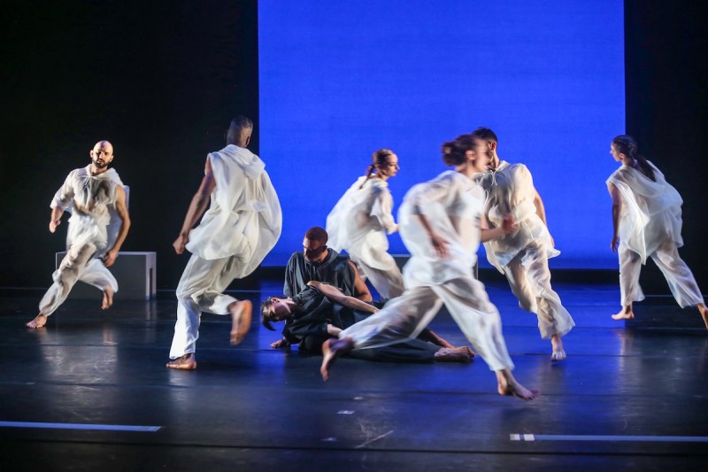 Se&aacute;n Curran Company dancers dressed in white perform onstage against a blue background.