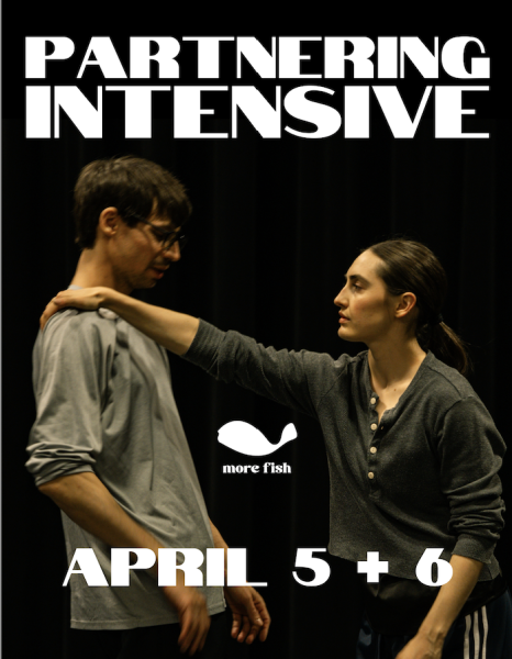 A dancer with long brown hair tied back in a ponytail holds the shoulder of a dancer with short brown hair.