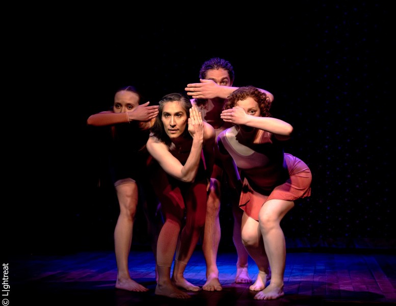 Four performers lean toward the camera covering their eyes or ears