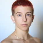 Dancer posing for a headshot, photographed from their shoulders up.