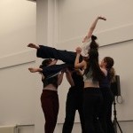 A group of dancers in a studio performing a lift 