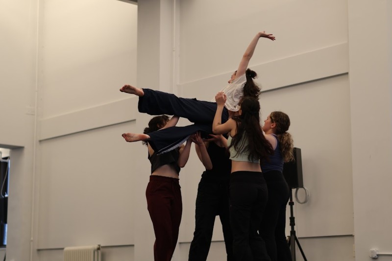A group of dancers in a studio performing a lift 