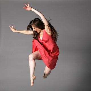 A dancer in a pink dress and flowing hair jumps into the air