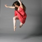 A dancer in a pink dress and flowing hair jumps into the air