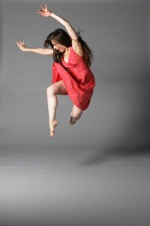 A dancer in a pink dress and flowing hair jumps into the air