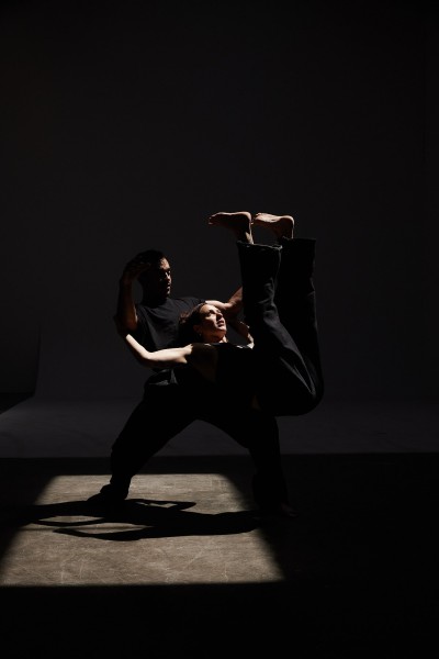 One dancer lifts another off the ground on his thigh 