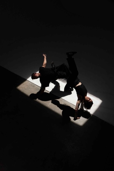 two dancers upside down in a bridge position with their shadows cast below them