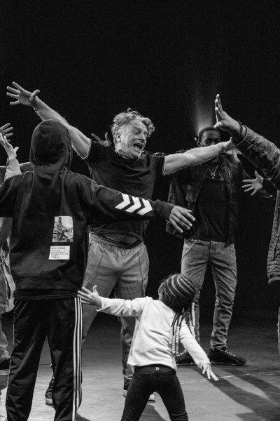 Bill Bowers posing with arms outstretched surrounded by students copying the pose.