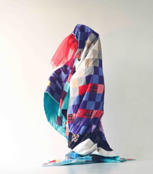 A woman in a quilted colorful blanket 