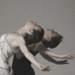 Two women are arched back with their chest to the sky and arms splayed to the sides