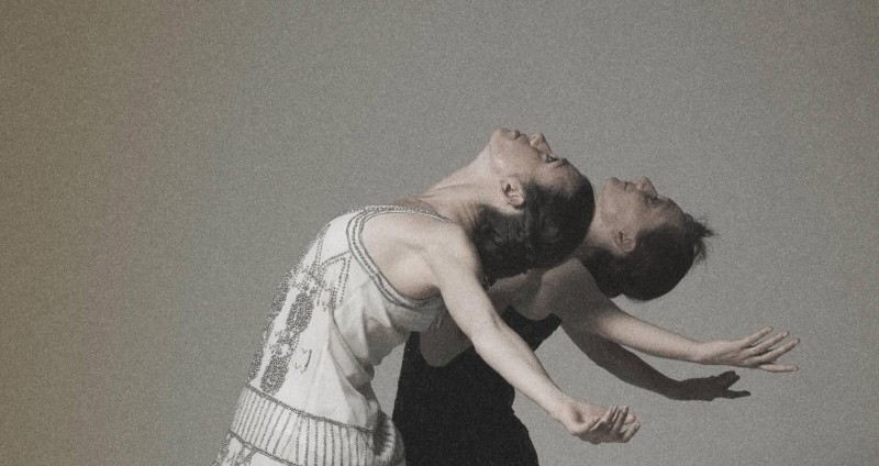 Two women are arched back with their chest to the sky and arms splayed to the sides