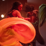A woman dancers in a yellow flowing skirt.