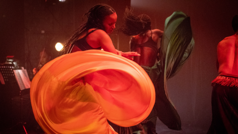 A woman dancers in a yellow flowing skirt.