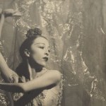 A woman holds her arms up in a dance movement.