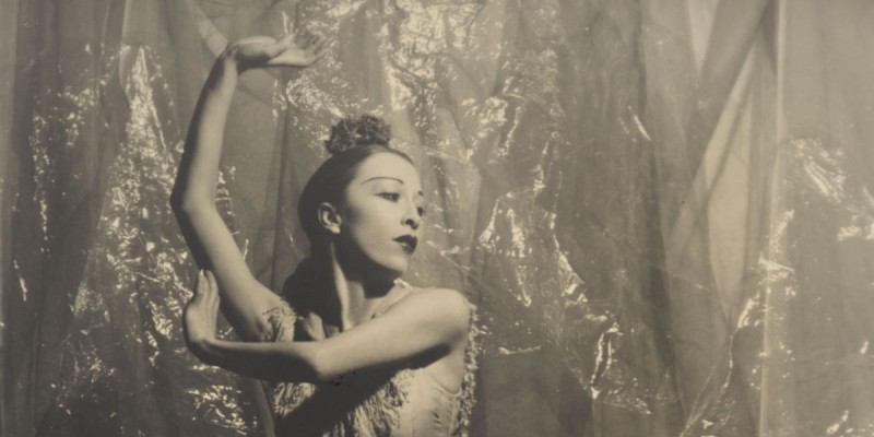 A woman holds her arms up in a dance movement.