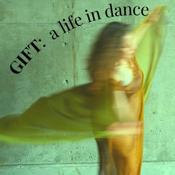 A woman holding a green scarf spins in a blur