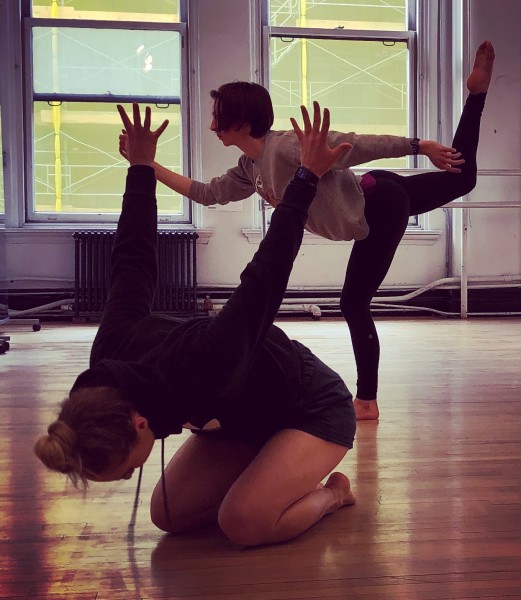 two dancers. one kneeling on floor with arms reaching up