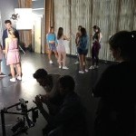Dancers on a film set, standing while framing the shot