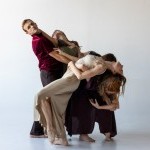 A group of dancers support one another as they arch backward
