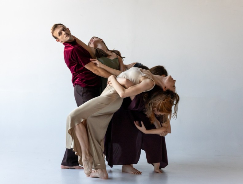 A group of dancers support one another as they arch backward