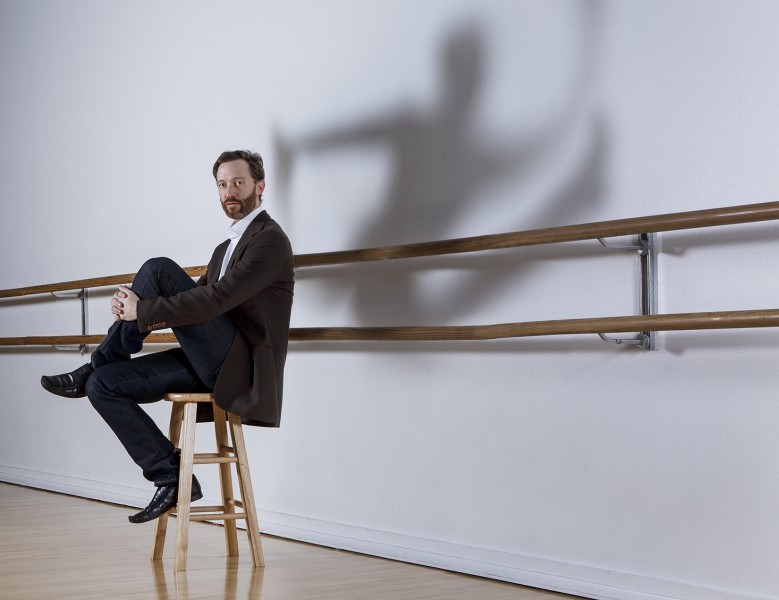 Photo of John Heginbotham with cool shadow of leaping dancer on wall behind him