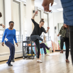 Tap dancers with Michelle Dorrance as the focal point in a studio dancing.