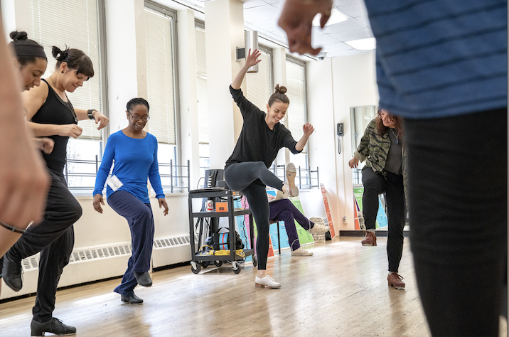 Tap dancers with Michelle Dorrance as the focal point in a studio dancing.
