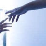 two hands reach towards each other in front of a window