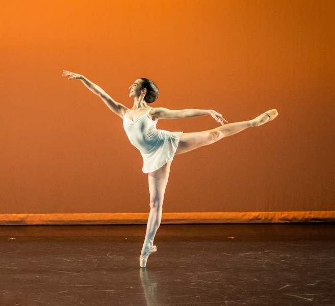 a ballerina stands on pointe in arabesque