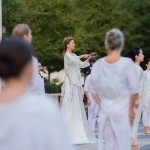 Outdoors, Dancer with a singing bowl surrounded by dancers in white