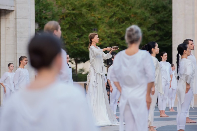 Outdoors, Dancer with a singing bowl surrounded by dancers in white