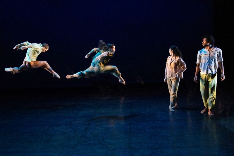 1 dancer leaping and 2 standing facing front with heads turned towards the dancer who is leaping   