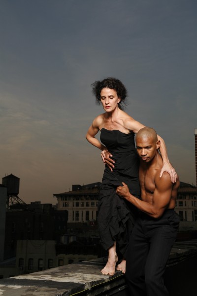 A woman walking on a ledge and held at the waist by a man