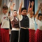 Elementary school students with arms raised above their heads in a flamenco dance class