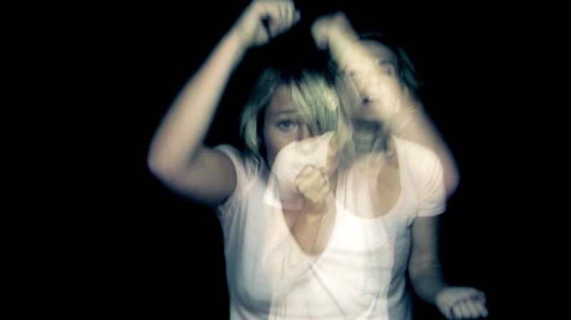 Image of two photos of a person wearing a white t-shirt, overlayed on top of one another so they blur together slightly.