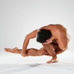 Male dancer twisting low and touching foot