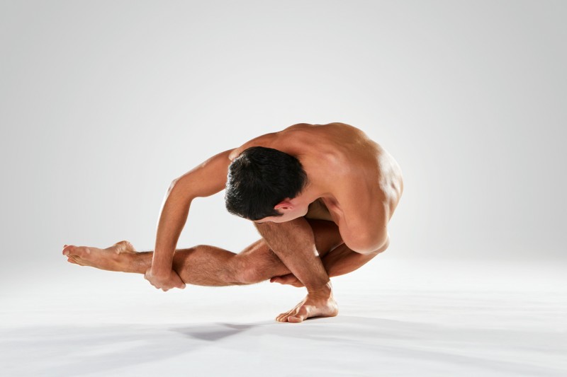 Male dancer twisting low and touching foot