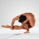 Male dancer twisting low and touching foot