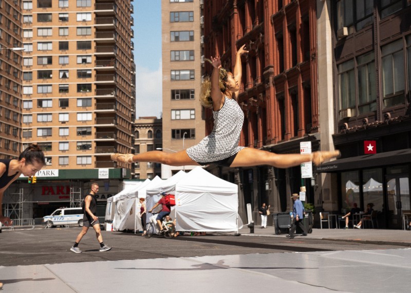 A dancer leaps with the city as a backdrop behind her