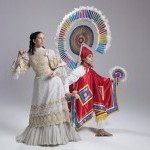 Two dancers pose in traditional period costumes from the Puebla region of Mexico