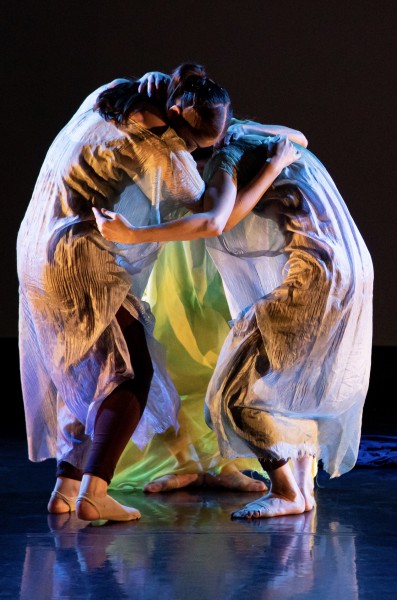 3 dancers in tunics huddled together