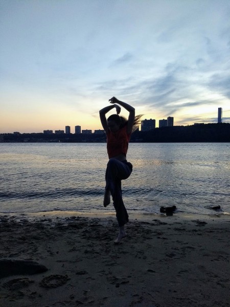 dancer by water, in big skip, arms over head