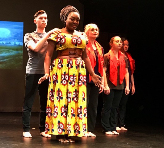 actor in front, dancer behind her with hands on her shoulders, others in back looking forward