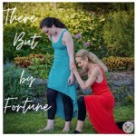 a dancer in orange dress lying on the back of a dancer n turquoise, outside in greenery