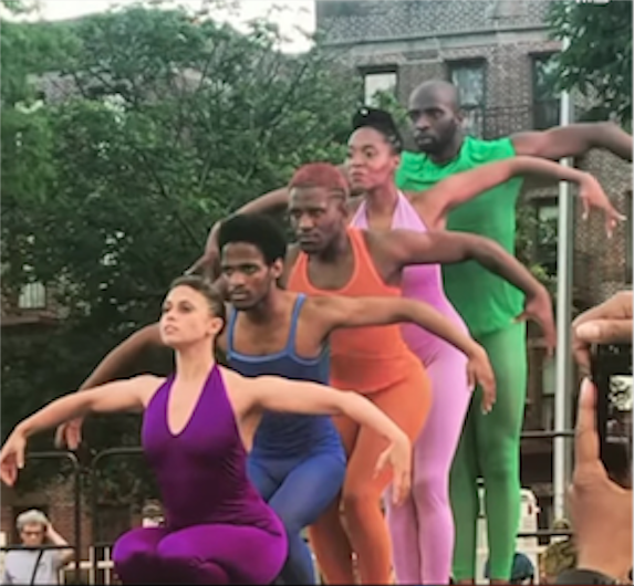 Dancers in different colored unitards from tallest to shortest with arms extended out to their sides like wings