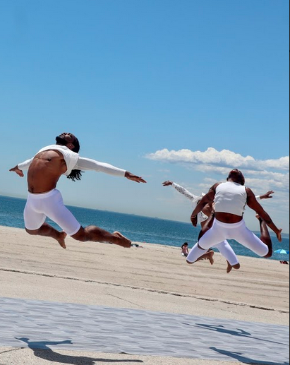 Dancers in white jumping in an arch position at the beach