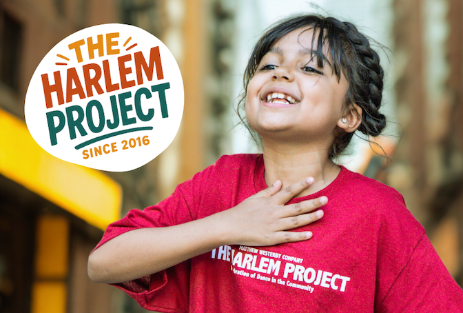 A young dancer in a red shirt places her hand on her chest
