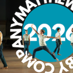 One dancer in a lunge is surrounded by others, dancing on a wooden floor.